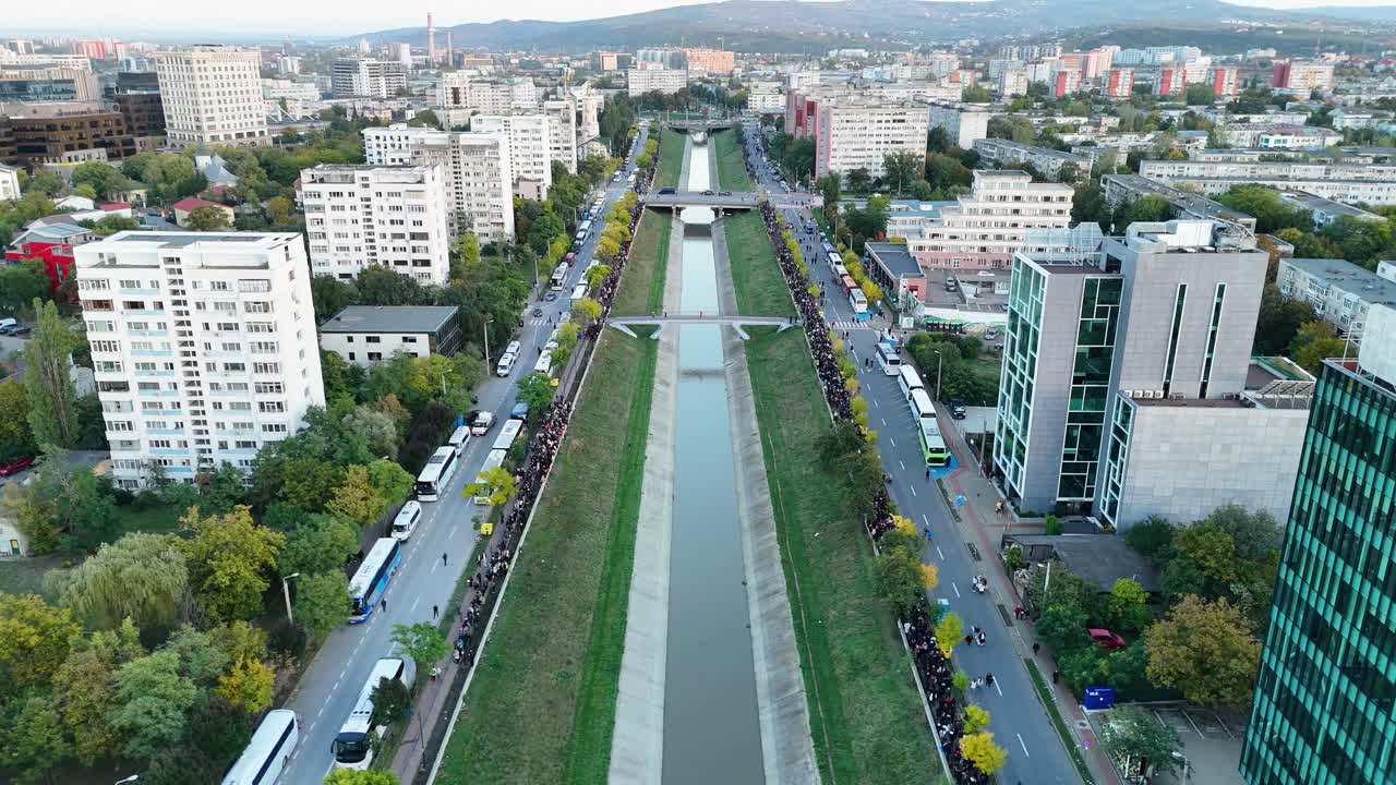 Ilmakuva Bahlui-joen vartta pitkin Iașissa, Romaniassa. Kuvassa näkyvät symmetriset kadut, moderni arkkitehtuuri ja paikallisen tapahtuman aikana kävelevät ihmisjoukot.