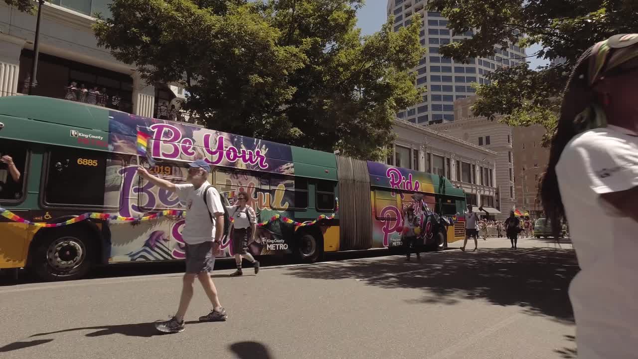 King county metro employees participating in the Seattle LGBTQ parade, waving rainbow flags