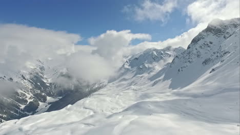 high aerial panoramic view in the snowy mountains with low hanging clouds