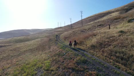 Hermosa-Antena-De-Jubilación-Pareja-De-Jubilados-A-Caballo-En-Un-Rancho-De-Montaña-En-Santa-Bárbara,-California