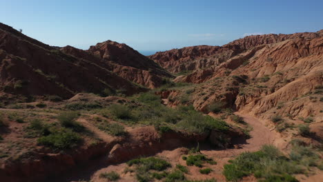 scenic aerial view flying through a rock formation in fairy tale canyon to reveal issyk-kul lake, kyrgyzstan