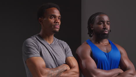 studio portrait of two male athletes sport training or exercising in gym folding arms