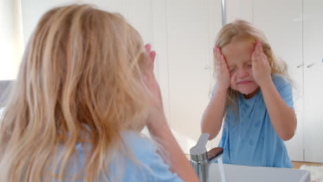 girl washing face and smiling at reflection