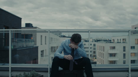 a sad man in a shirt smokes a cigarette on the balcony