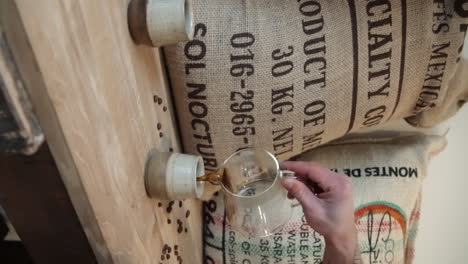 barista sirviendo café negro de una tetera de vidrio en una taza