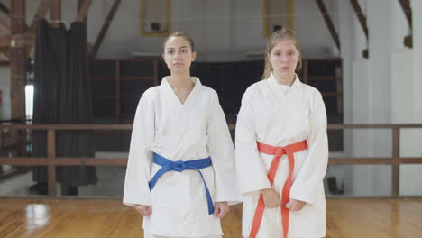 front view of focused martial artists lunging to sides in gym