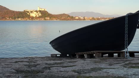 Fischerboot-Auf-Grund-Mit-Blick-Auf-Den-Lago-Maggiore-Und-Die-Festung-Angera-Im-Hintergrund