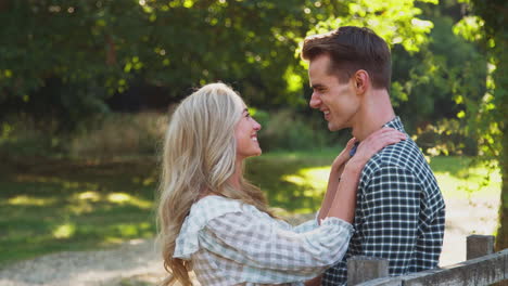 loving young couple meeting by fence on walk in countryside together and hugging