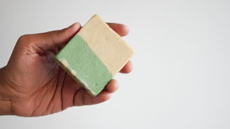 hand holding a bar of green and cream soap