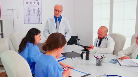 Nurse-taking-notes-while-elderly-medical-expert-explaining-viral-diseases