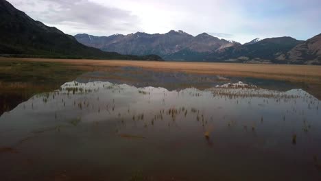 Malerischer-Landschaftlich-Ruhiger-Blick-Auf-Die-Yukon-Landschaft-über-Glänzendem,-Reflektierendem-Oberflächenwasser-Des-Kluane-Sees-Mit-Schafbergkette-Im-Hintergrund-An-Einem-Sonnigen-Tag,-Kanada,-Überkopf-Luftrückzug