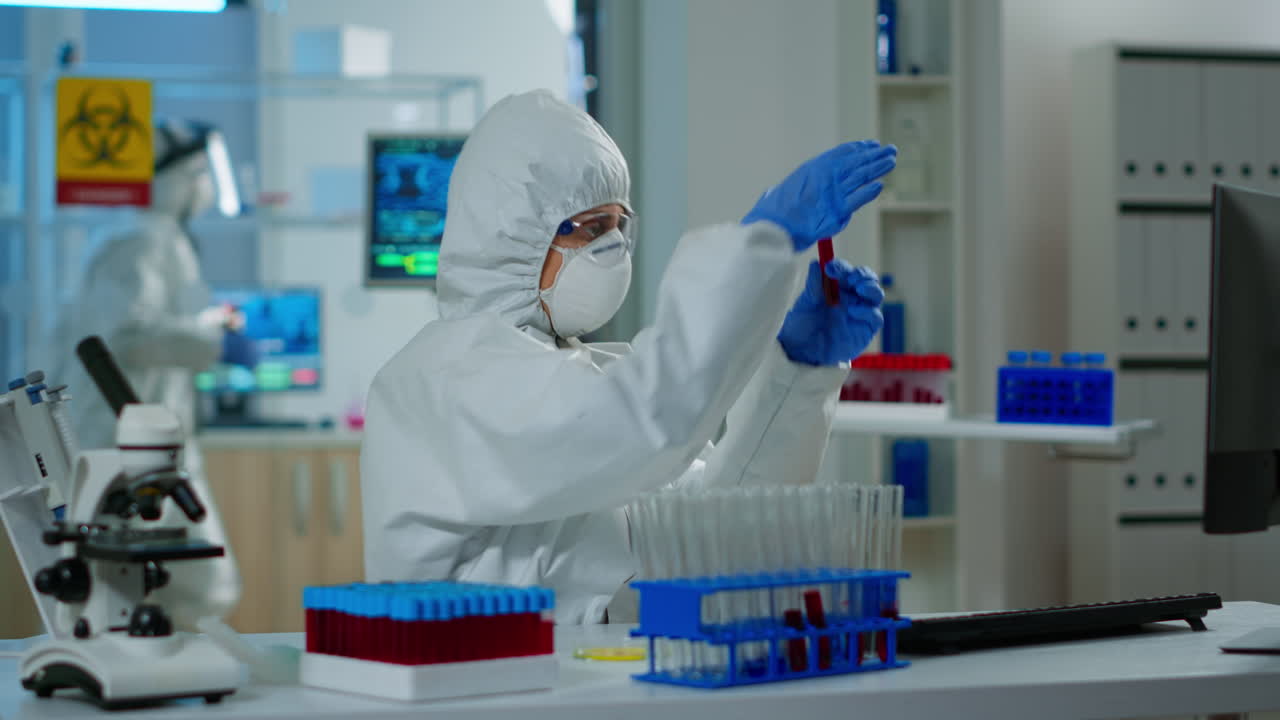 investigador en traje de abrigo sosteniendo tubos de ensayo con muestra de sangre