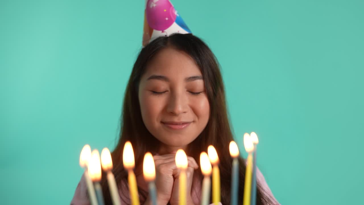 mujer asiática feliz soplando velas en su cumpleaños