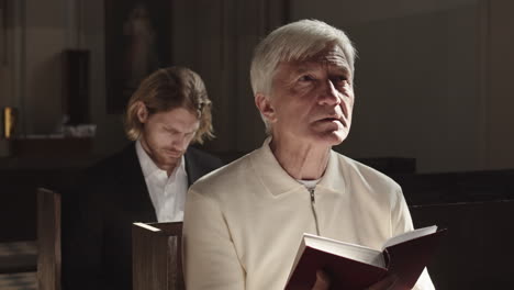 two male parishioners reading bible in church