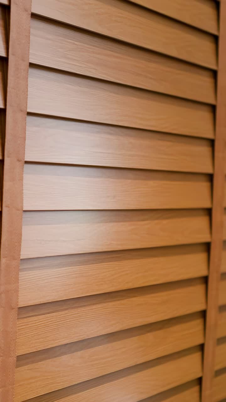 Le persiane veneziane in legno si chiudono lentamente, bloccando la luce solare naturale dall'entrare in un moderno spazio interno domestico.
