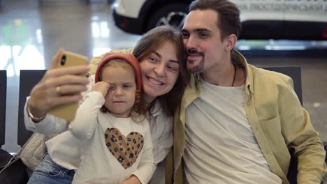 young family doing a selfie with smart phone while waiting for airplane