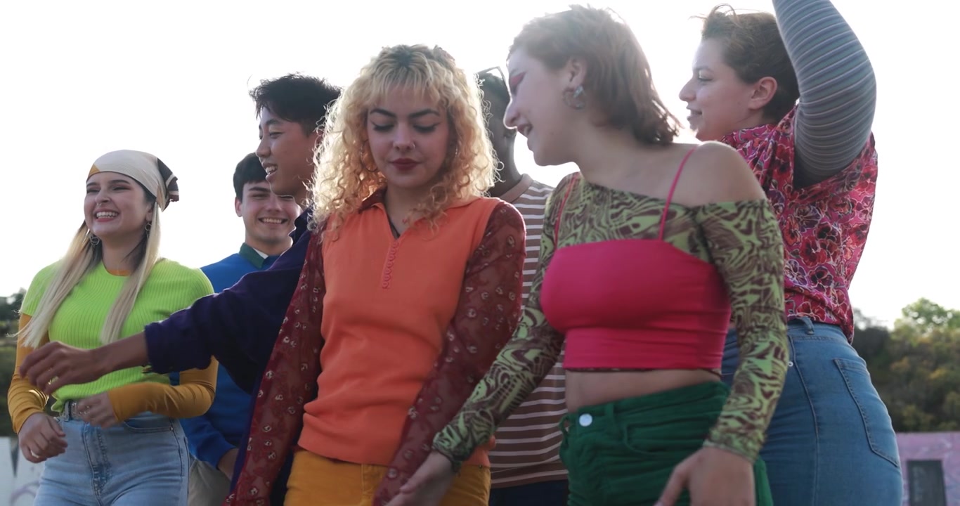 Glade multietniske unge venner danser sammen udendørs