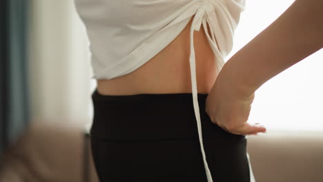 여성이 스포츠 바지를 집에서 가까이에서 훈련시니다. 단순하고 편안한 운동복을 입은 여성이 국내 체육관에서 느린 운동을합니다.