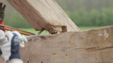 trabajador desmontando vigas de madera del techo en el sitio de deconstrucción