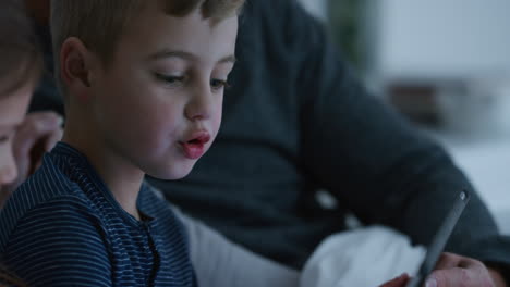 familia usando computadora tablet madre y padre viendo a los niños jugando juegos en un dispositivo de pantalla táctil aprendiendo divirtiéndose juntos en casa antes de acostarse metraje 4k