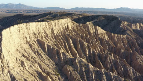 A-mesmerizing-aerial-shot-advances-over-the-stunning-rock-formations-of-the-Badlands,-showcasing-their-rugged-beauty-and-unique-geological-features