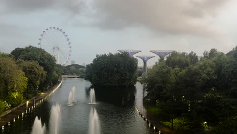 Fountains,-Supertree-Groves,-And-Singapore-Flyer-Ferris-Wheel-Seen-At-Gardens-By-The-Bay-At-Dusk