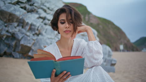 chica de la costa disfrutando de un libro en un día nublado de primer plano. centrado mujer hermosa relajante