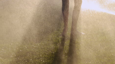 Active-barefoot-woman-run-on-the-green-grass-in-jets-of-water.-Slow-motion-4k-video.-Y