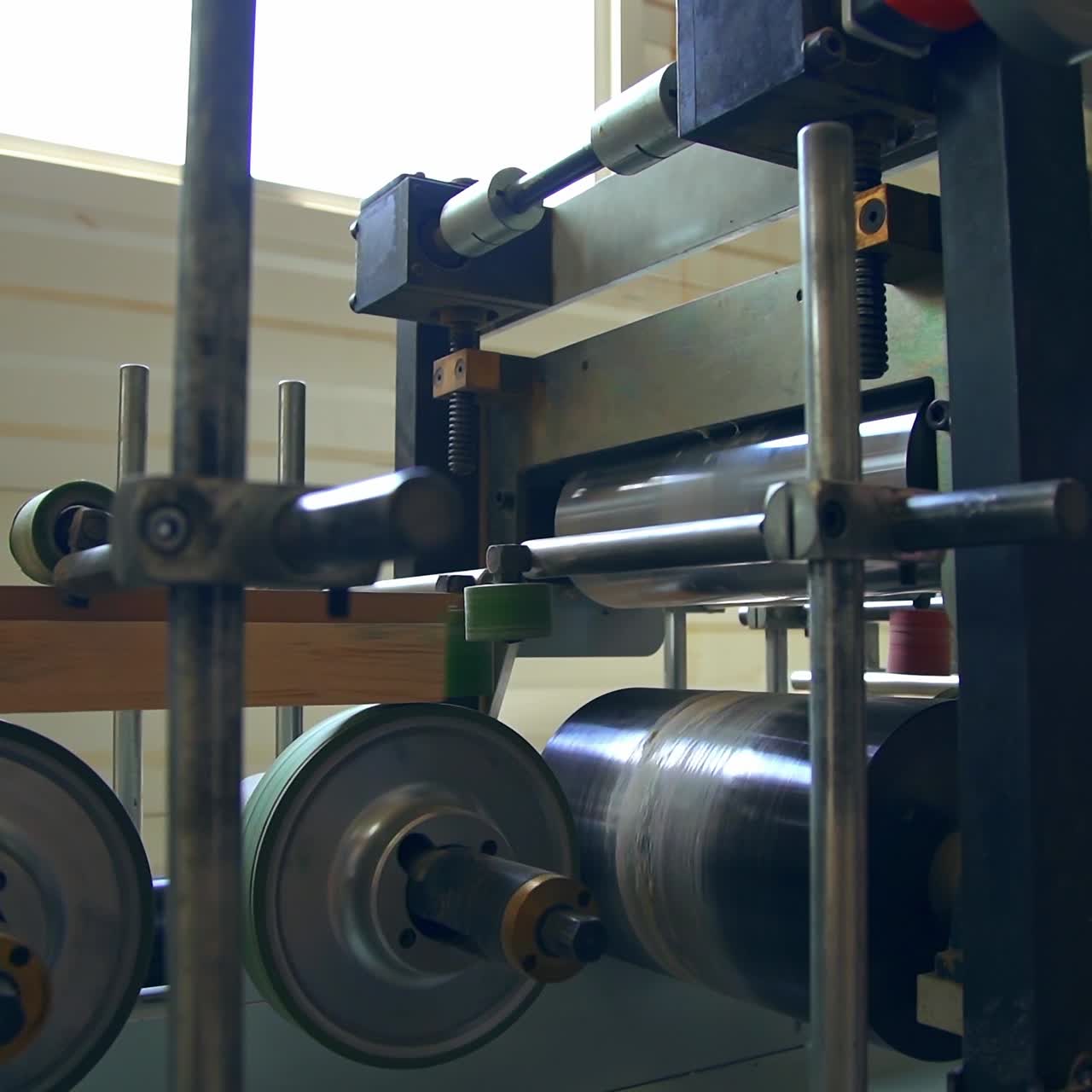 Automatic equipment at modern woodworking factory. Wooden bar moving quickly along the line due to rotating shafts