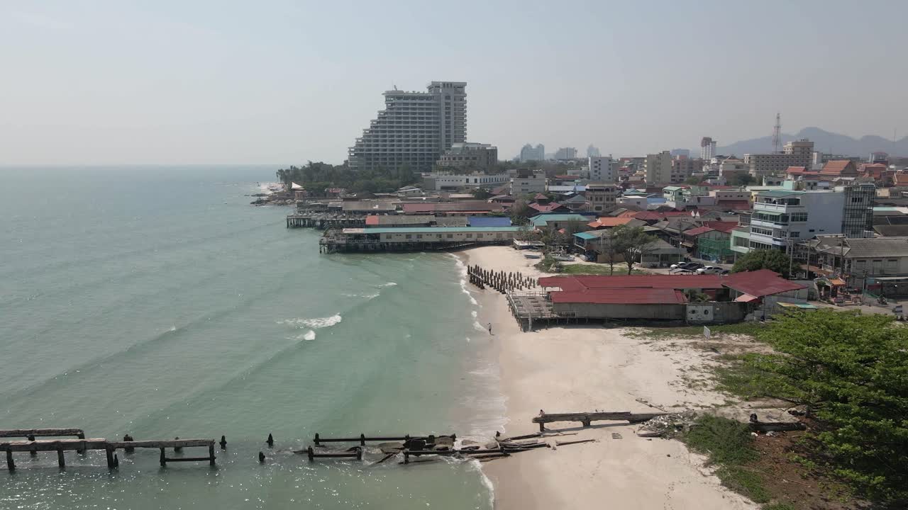 Flyover new and old fishing piers on sand beach, Hua Hin city skyline