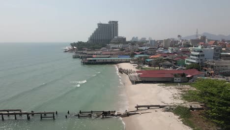 flyover new and old fishing piers on sand beach, hua hin city skyline