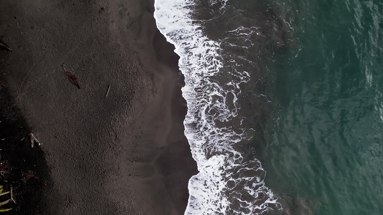 карибская вода промывает вулканический темный пляж гваделупы, воздушный сверху вниз