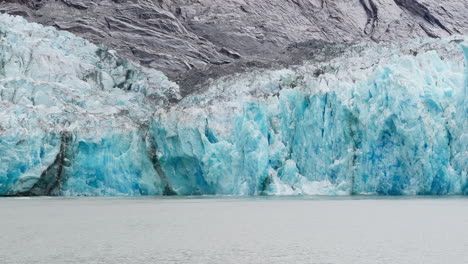 this is a close-up shot of a piece of the blue ice wall calving off the dawes glacier in endicott arm near juneau alaska. it shows white seagulls flying around showing scale