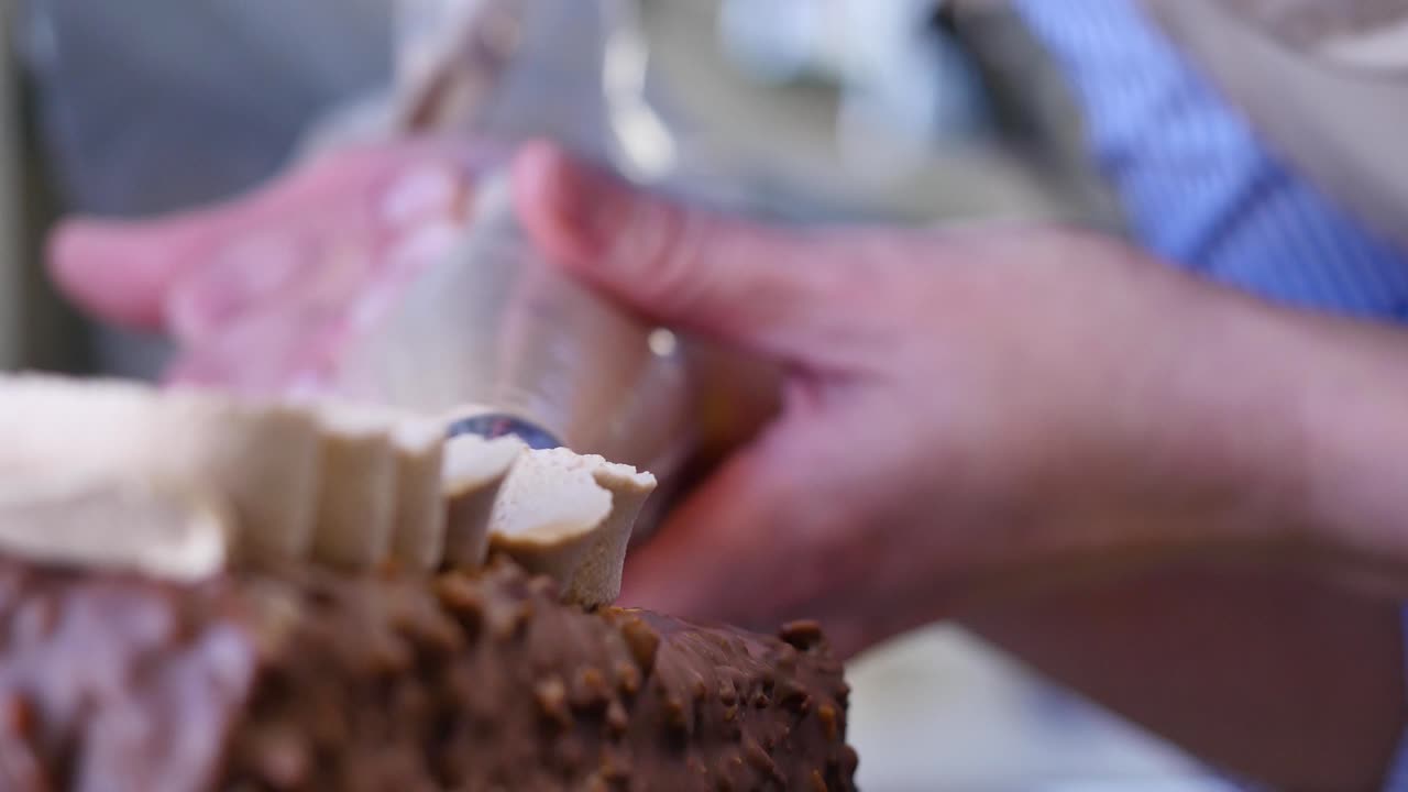 Person Decorating Chocolate Cake with Piping Bag