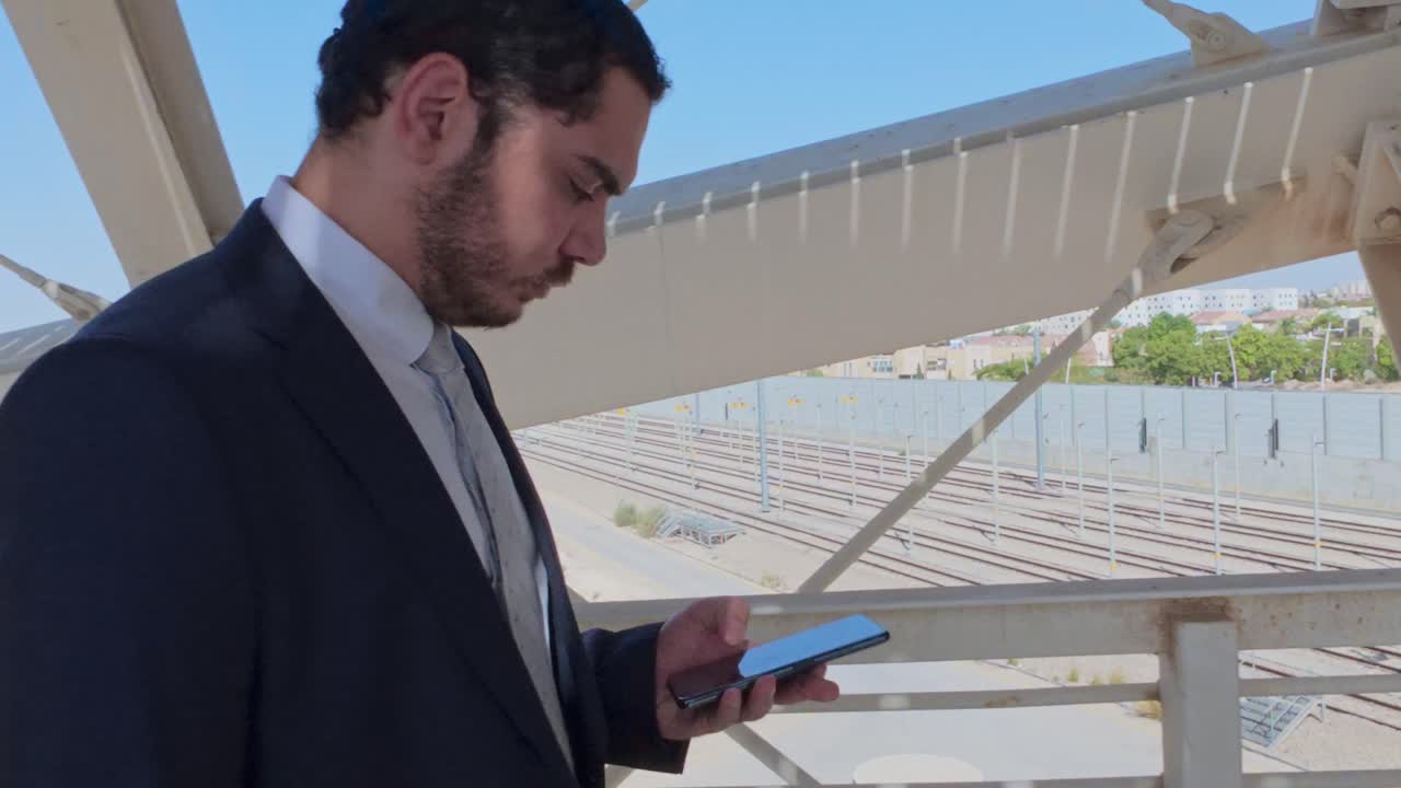 Serious Businessman in a Suit Walking on a Modern Pedestrian Bridge