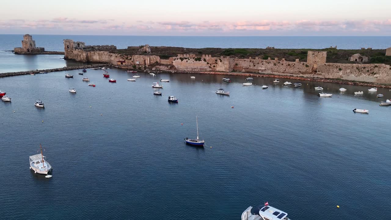 Methoni,Messenia,Peloponnese,Aerial panoramic view,pan right and backwards from Bourtzi Tower towards Methoni Castle.Lot of small boats on buoys on crystal clear waters,small beach in front of Castle