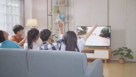 asian teenagers playing video games and celebrating victory at home