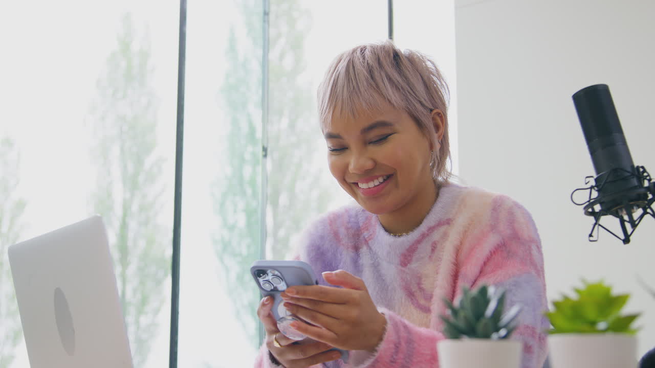 vlogger femminile con microfono in diretta streaming che guarda il telefono cellulare