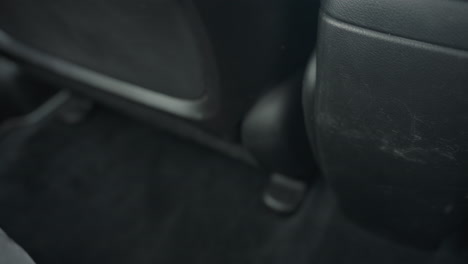 close up of driver seat sliding back and forth on black carpeted car floor with natural daylight entering vehicle interior and creating soft highlights on textured surfaces