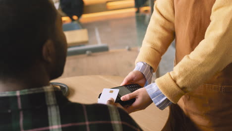 Back-View-Of-An-Unrecognizable-Man-Paying-Waiter-With-Contactless-Credit-Card-In-Cafe