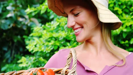 hermosa mujer sosteniendo una canasta de mimbre con tomates