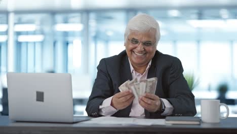 happy indian senior businessman counting money