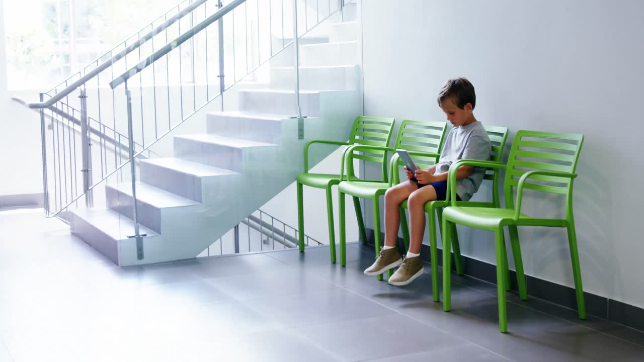 병원 복도 에서 디지털 태블릿 을 사용하는 소년