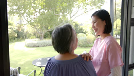 smiling caregiver supporting senior asian woman in garden, enjoying outdoor time together