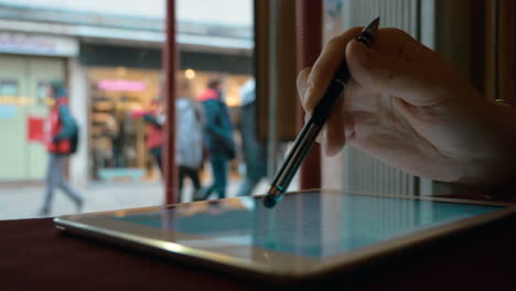 Frau-Arbeitet-Mit-Touchpad-Am-Fenster-Im-Café