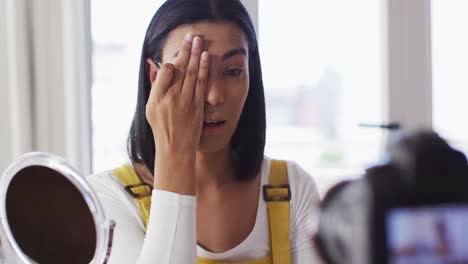 집에서 메이크업 블로그를 녹화하는 혼성 인종 성 유체 블로거