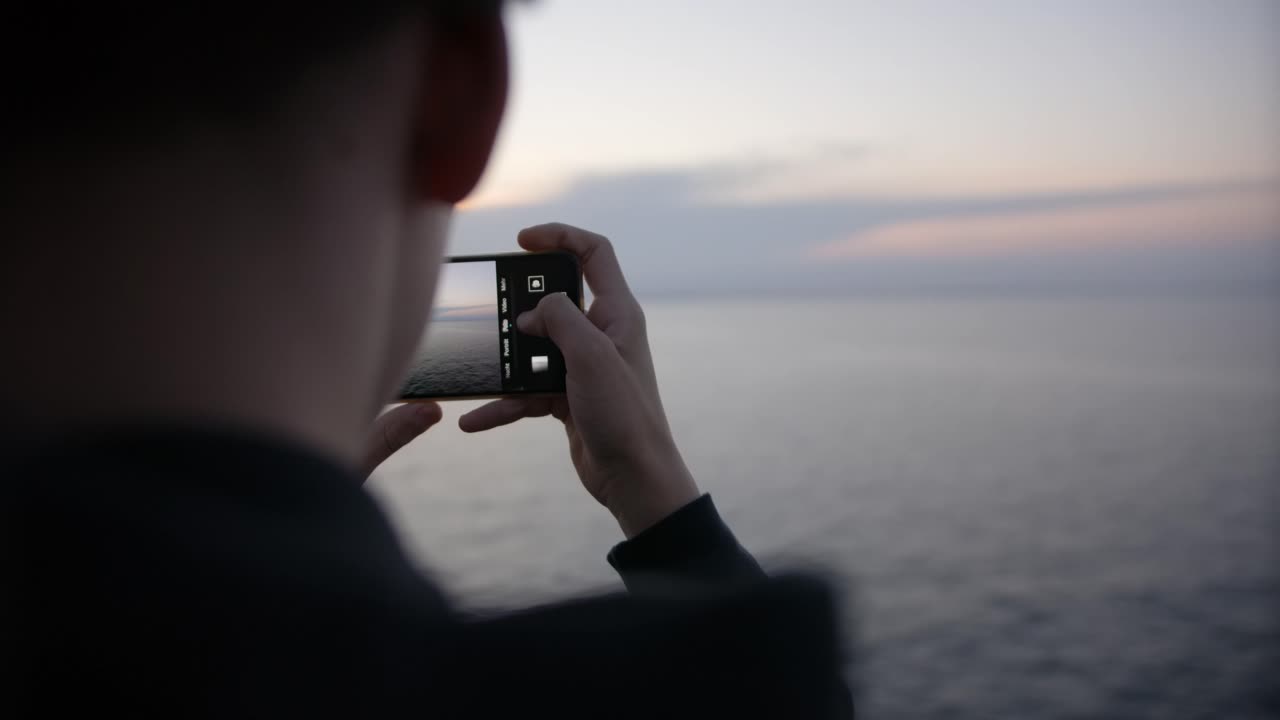 tomando fotos del amanecer con smartphone en ferry a noruega en cámara lenta