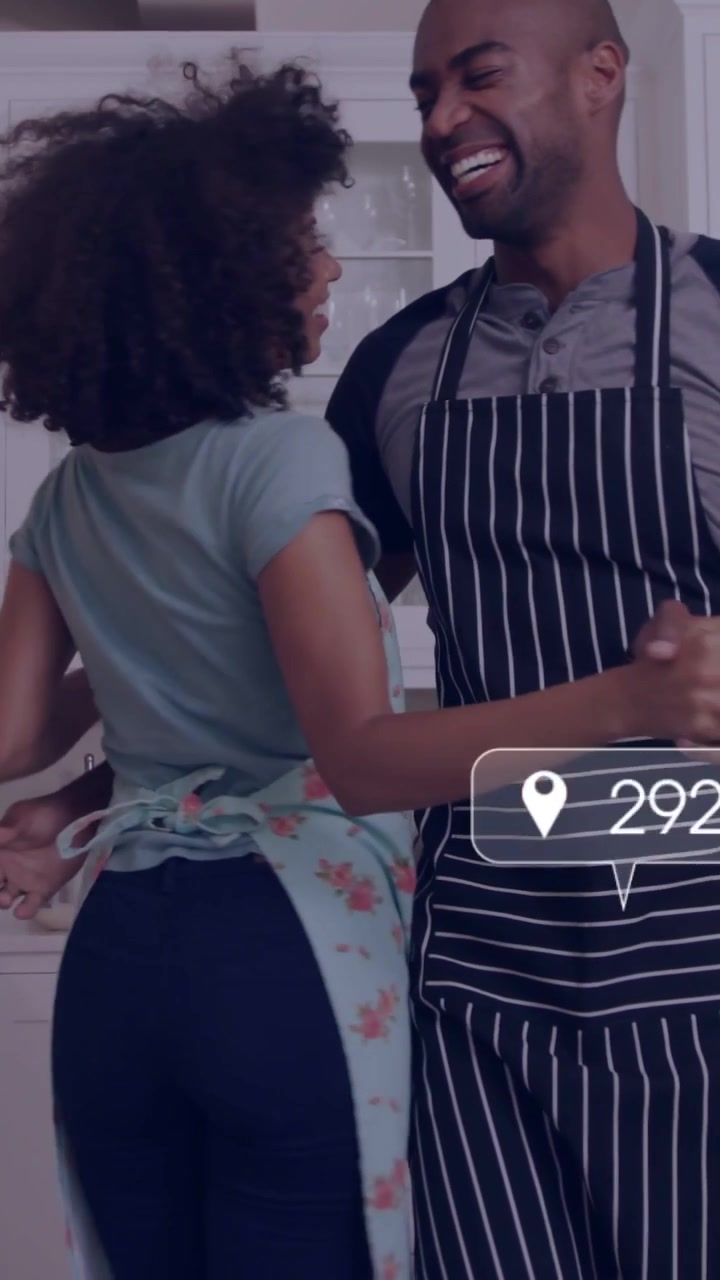 Vertical video: Man reaching partner, sparking playful dancing in kitchen, social likes over couple