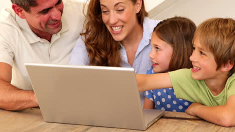 Familia-Sonriente-Usando-Una-Computadora-Portátil-Juntos-En-La-Mesa