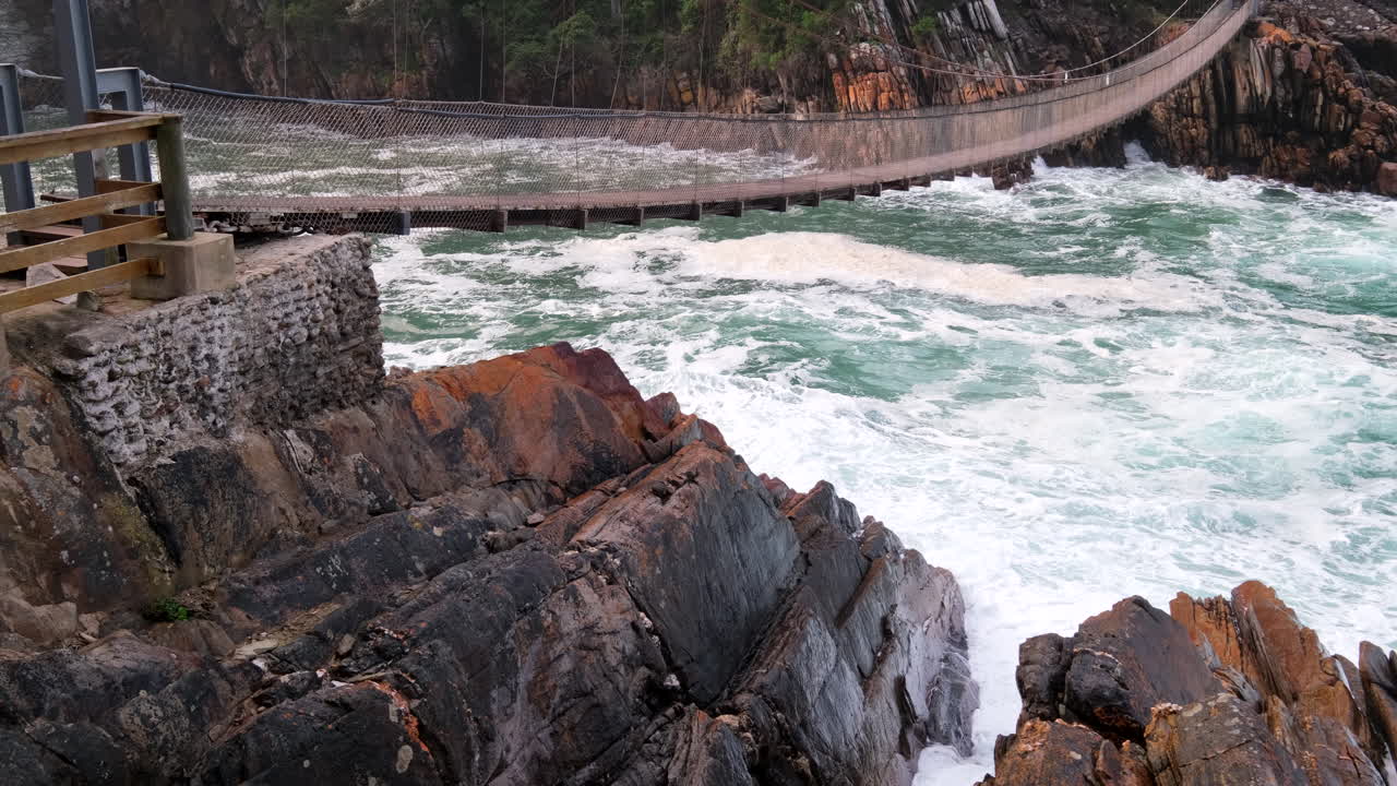 Frothing seawater on stormy day under Storms River mouth suspension bridge